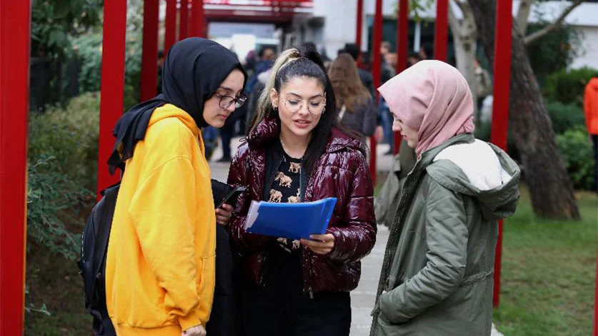Three girls standing in a public place wearing hijab and not wearing hijab in Turkey