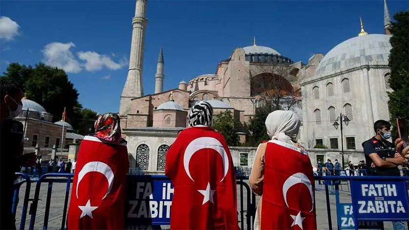 Women standing wearing hijab and Turkey flag